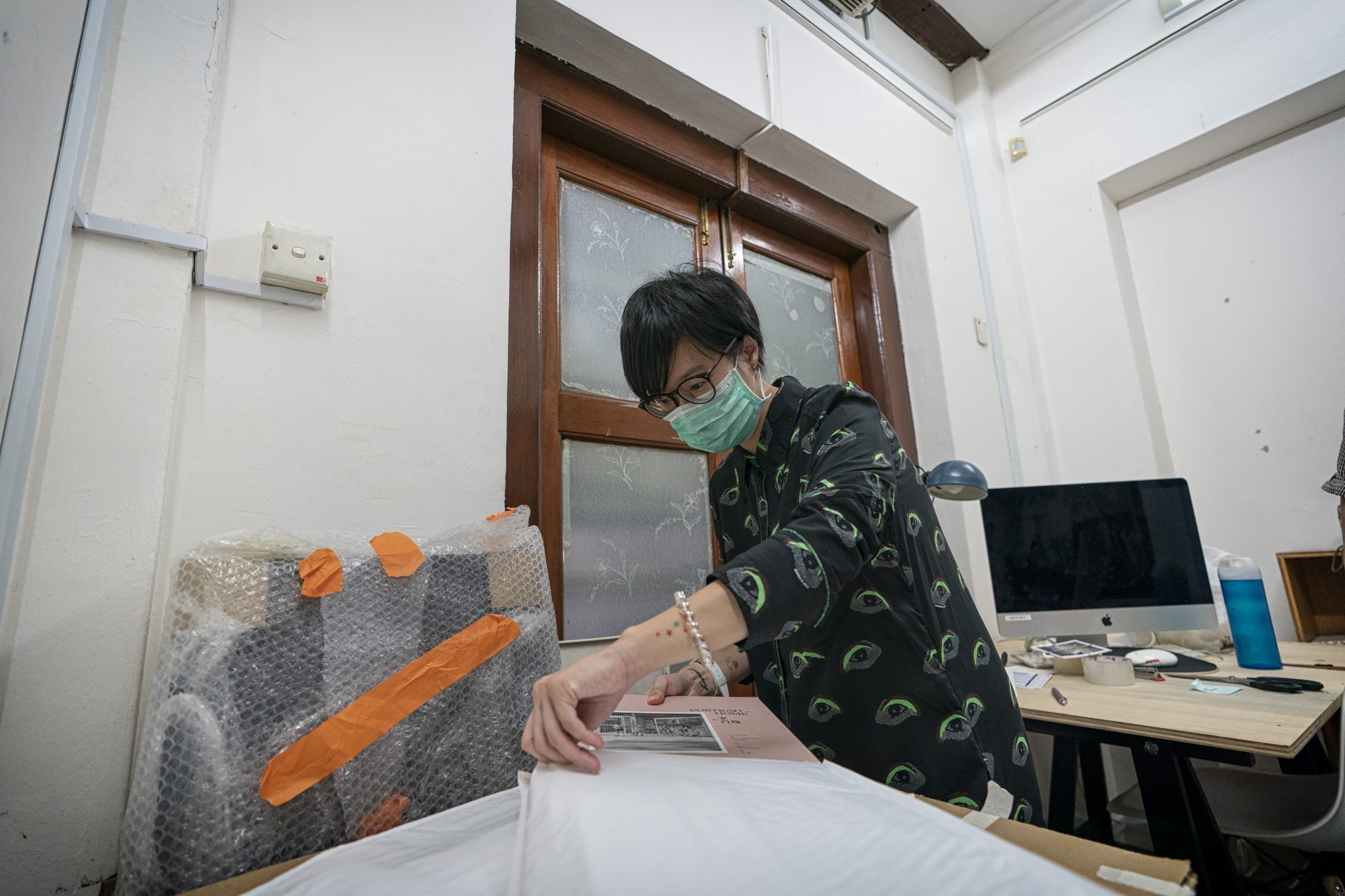 Objectifs senior manager, Ms Leong Puiyee, packs copies of photo book, Portraits of Home, by 87-year-old photographer Mr Lim Kwong Ling, for delivery to buyers. Mr Lim’s book launch, scheduled for April, was cancelled because of Covid-19. Photo by: Bryan van der Beek